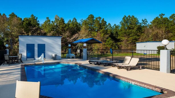A swimming pool with lounge chairs, a covered seating area, and a fenced deck. - Quality Inn near Parc Natchitoches (Natchitoches)