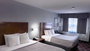 A hotel room with two beds, a nightstand, a lamp, a window with curtains, and a carpeted floor. - Quality Inn near Parc Natchitoches (Natchitoches)
