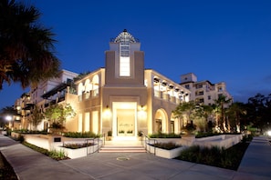 A hotel with a central tower, multiple balconies, and a well-lit entrance.