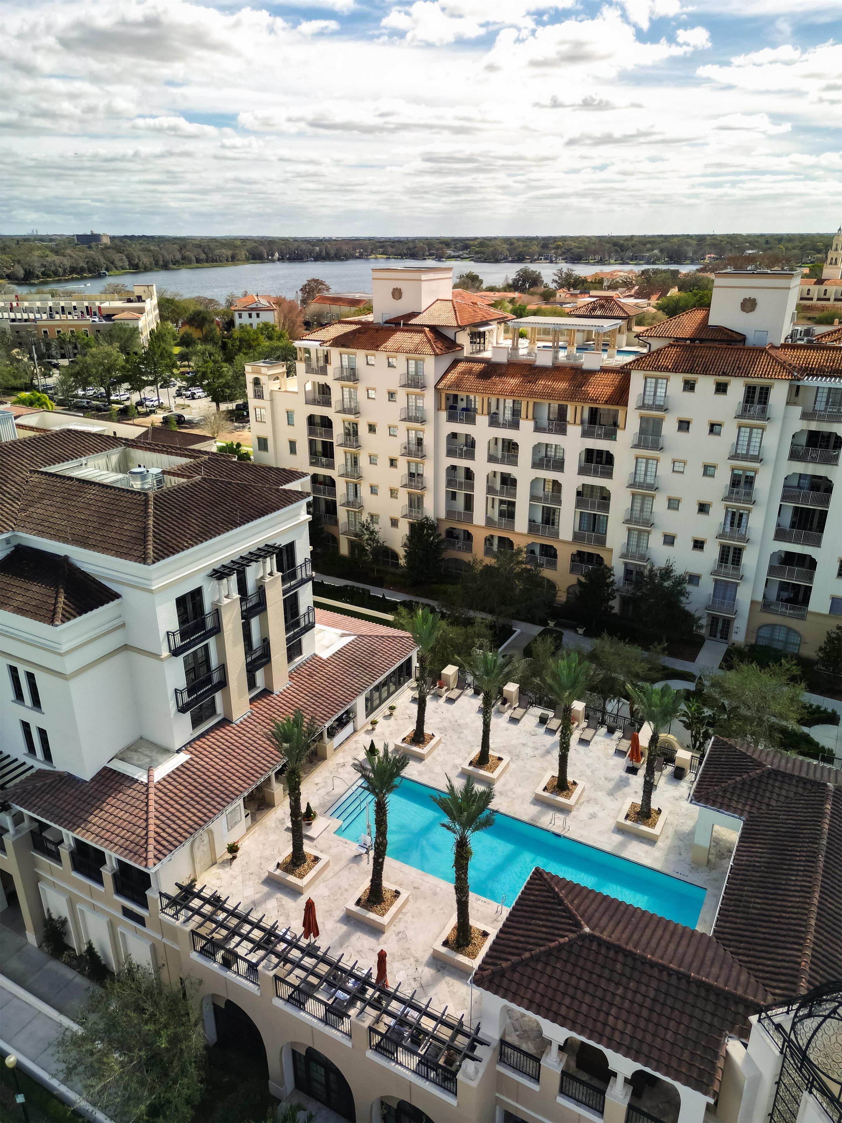 Un hotel con piscina rodeada de palmeras y vista a un lago.