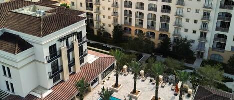 Un hotel con piscina rodeada de palmeras y vista a un lago.