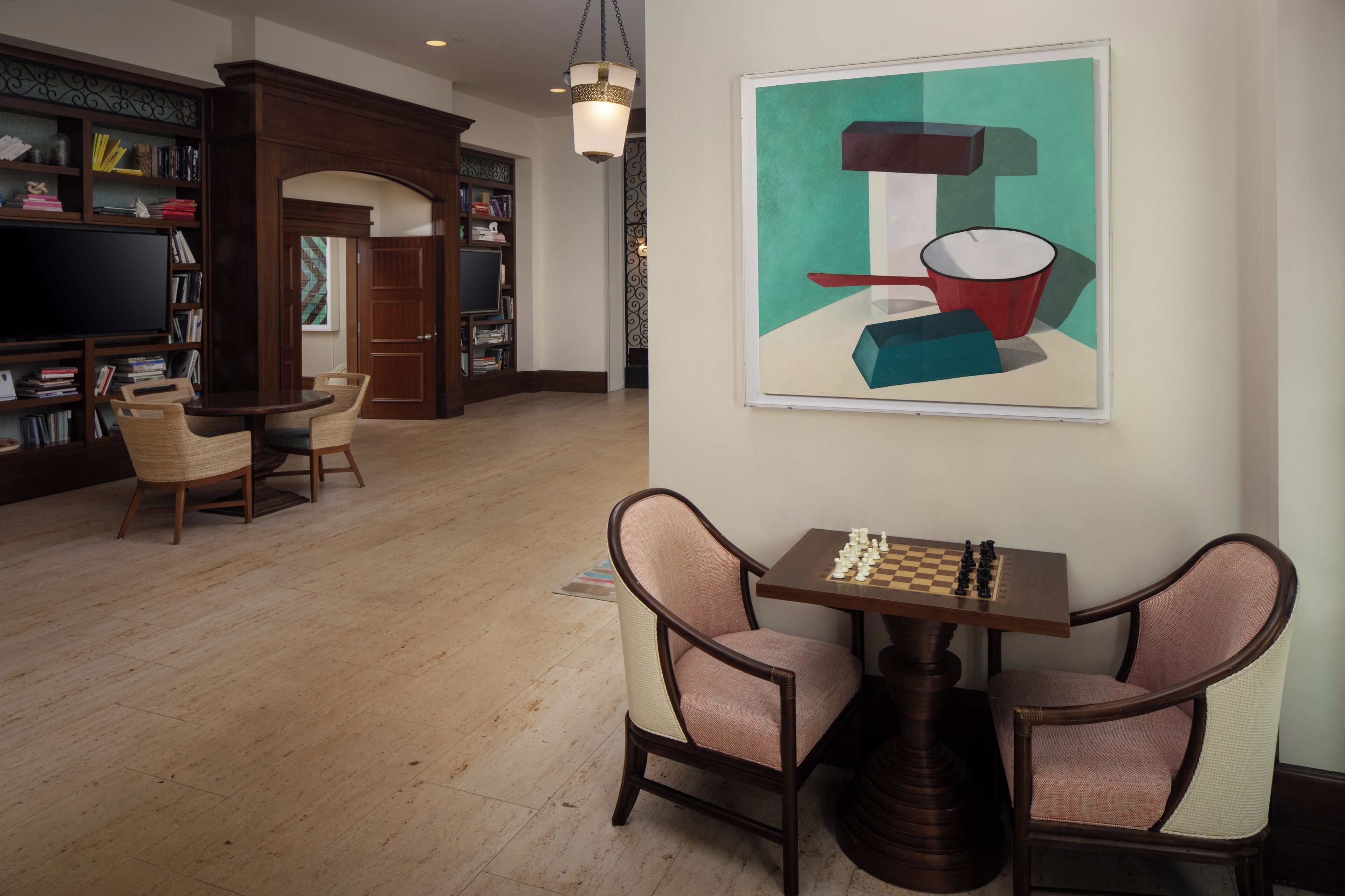 A spacious living room with a wooden floor, a bookshelf, a television, and a chess table.