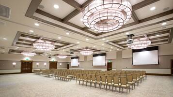 A conference room with rows of chairs, a large screen, and a ceiling with recessed lighting.