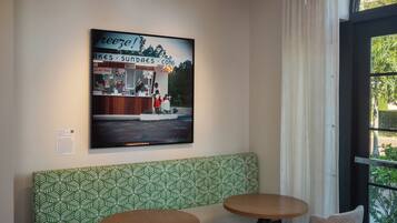 A seating area with a green patterned bench, two round tables, and hanging pendant lights.