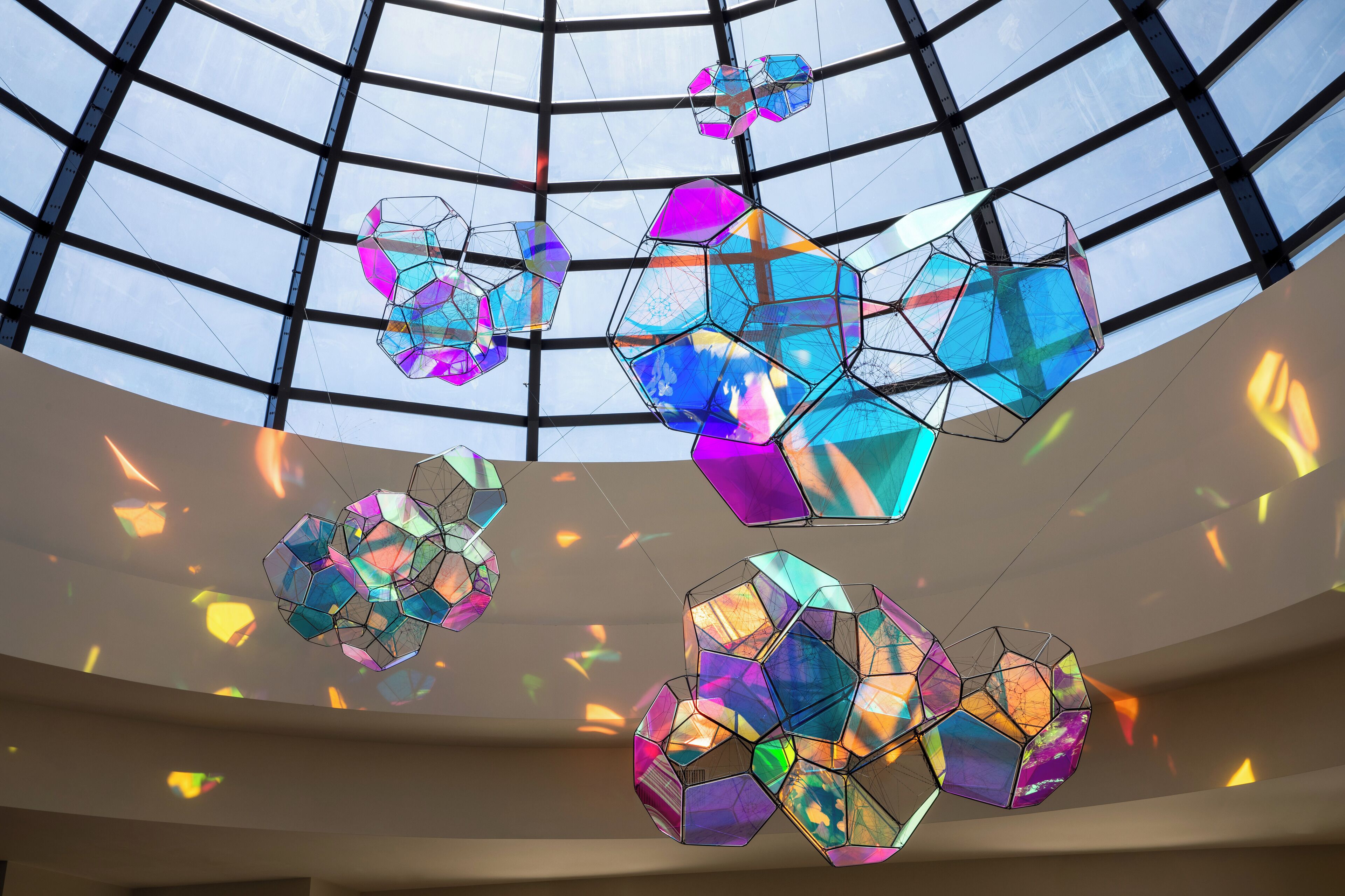 A modern interior with a glass ceiling and geometric light fixtures.