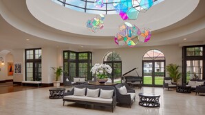 A spacious lobby with a high ceiling, large windows, and a grand piano. - The Alfond Inn (Winter Park)