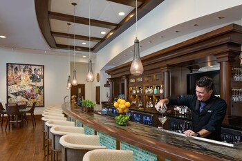 A spacious lobby with a high ceiling, wooden beams, and a large stained glass window. There are multiple seating areas with sofas and chairs, and a dining area in the background. at The Alfond Inn