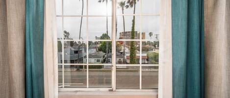 Una ventana con vista a una zona residencial, con casas y palmeras.