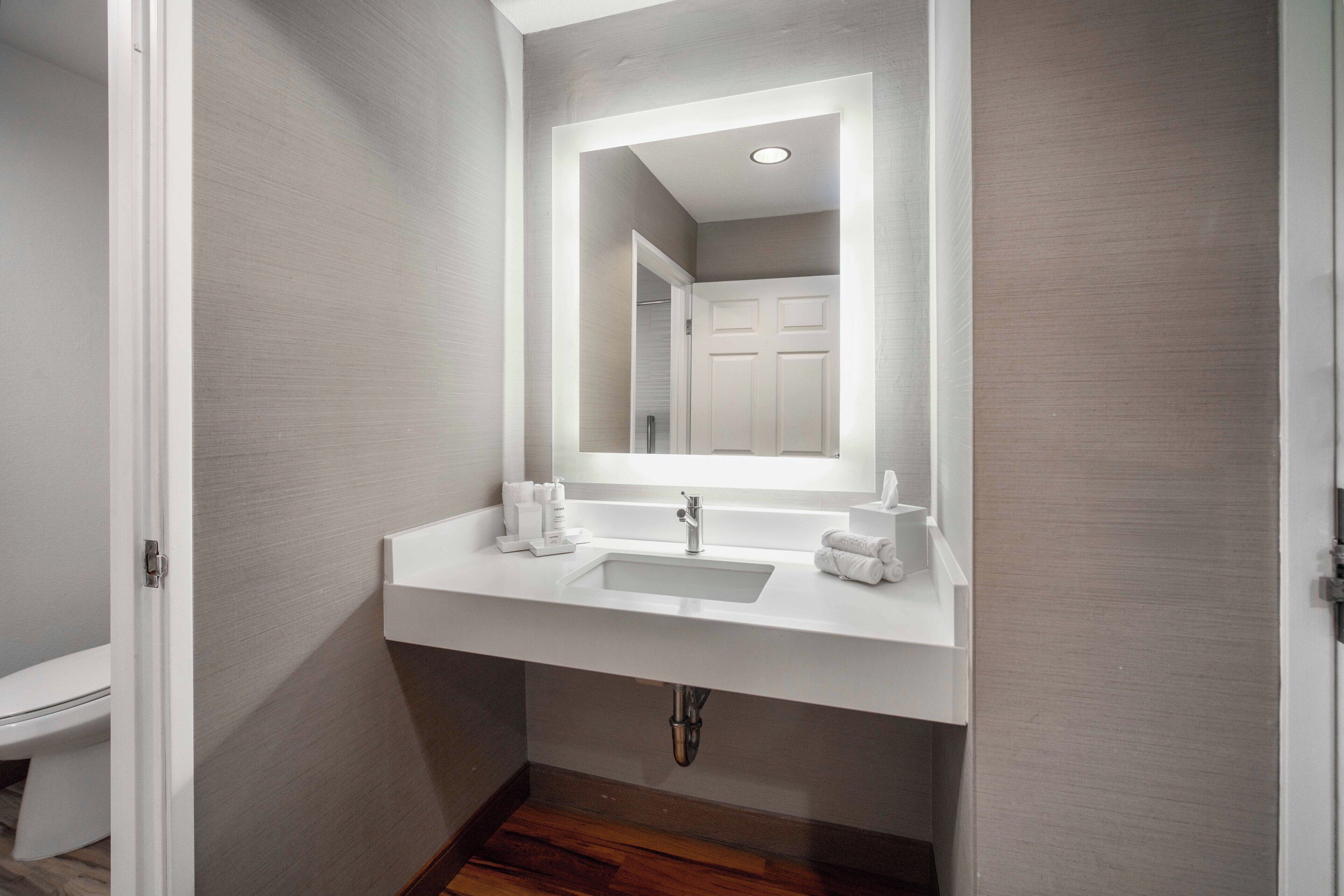 A bathroom with a white sink, mirror, and towel rack.