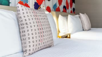 Un lit bien fait, avec une literie blanche et un oreiller orné d’un motif de lettres.