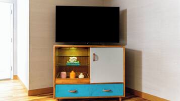 A corner room with a wooden cabinet, a television on top, and a door to the left.