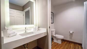A bathroom with a white sink, mirror, and toilet.