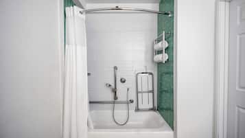 A bathroom with a white bathtub, a shower, and a towel rack.