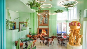 Ein Restaurant mit grünen Farbtönen, Holzmöbeln und einem zentralen Kamin.