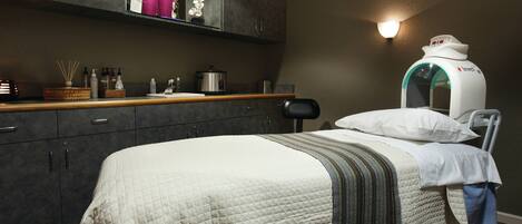A bedroom with a bed, a bedside table, a mirror, and a wall-mounted device.