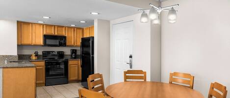 A modern kitchen with wooden cabinets, a black refrigerator, and a built-in oven.