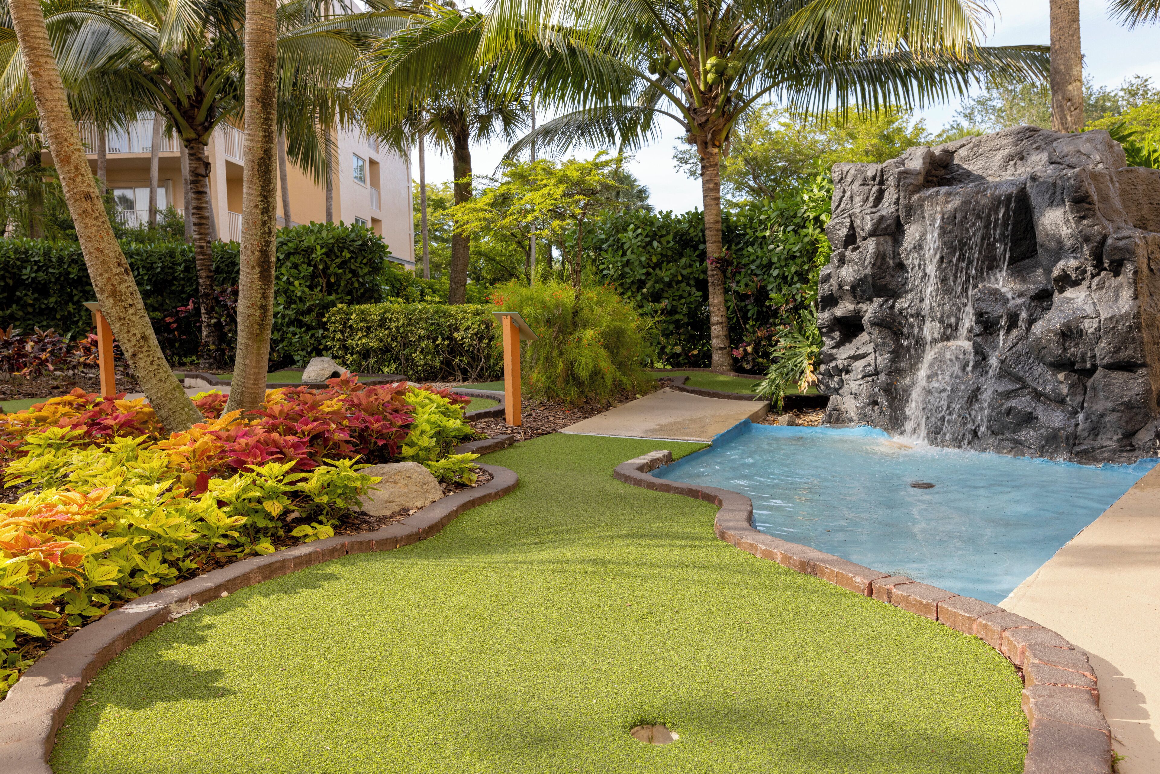 A landscaped area with a water feature, palm trees, and a pool.