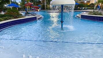 Relax by the pool surrounded by lounge chairs and umbrellas, with a central fountain and multi-story views.