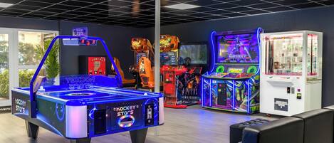 Un espace de jeux équipé d’une table de billard, de jeux d’adresse avec des pinces et de jeux d’arcade.