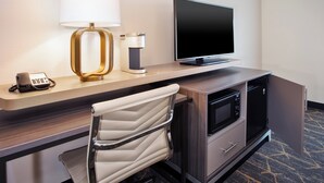 A hotel room with a desk, a television, a coffee maker, a telephone, and a microwave. - Holiday Inn Canton (Belden Village) by IHG (Canton)