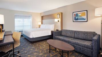 A hotel room with a bed, a sofa, a desk, and a chair.