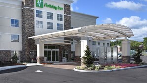 A Holiday Inn hotel with a modern design, featuring a covered entrance and a landscaped area with plants and flowers. - Holiday Inn Canton (Belden Village) by IHG (Canton)