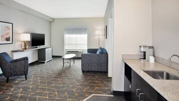 A modern hotel room with a living area, kitchenette, and a sofa.