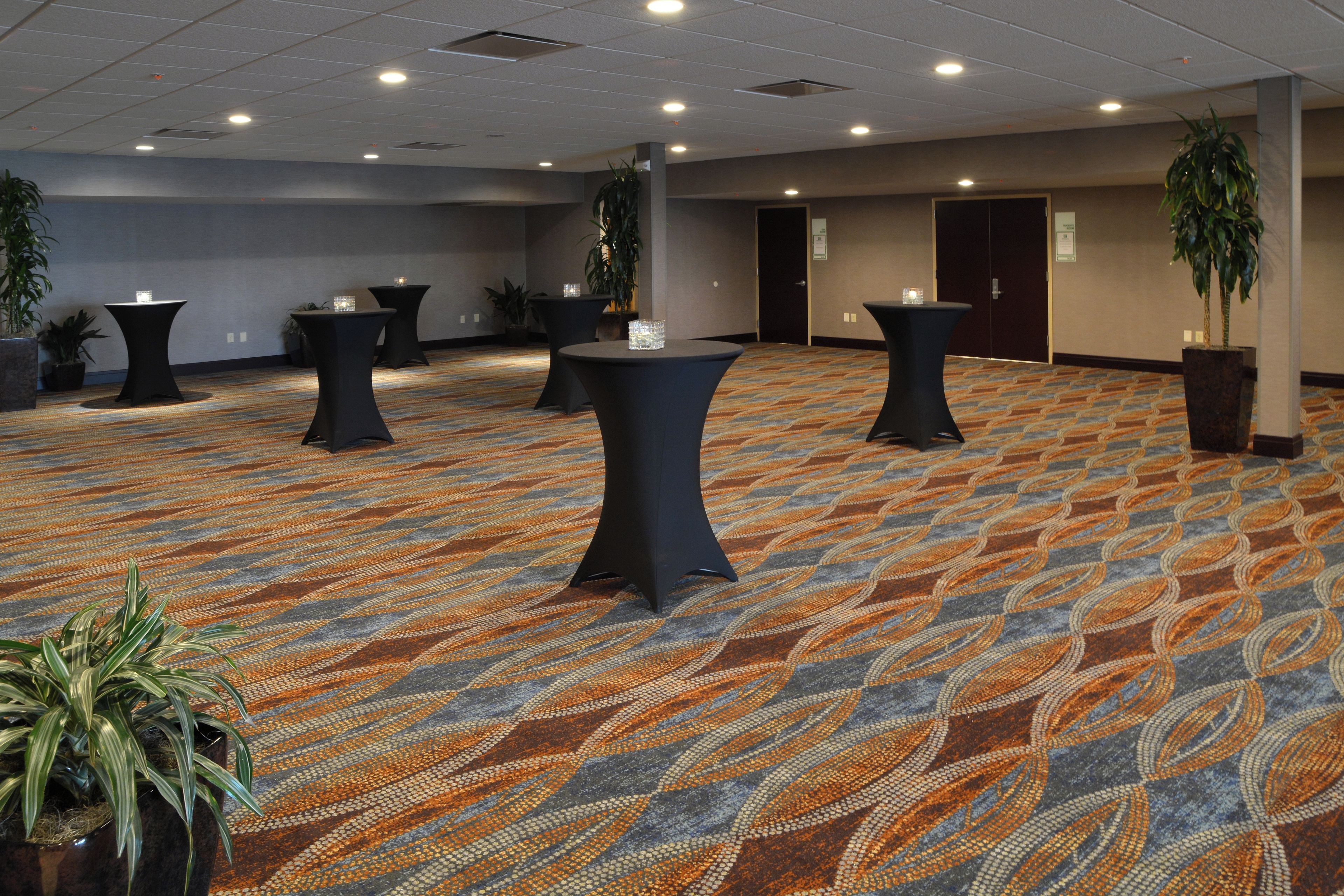 A conference room with multiple tables, chairs, and potted plants.