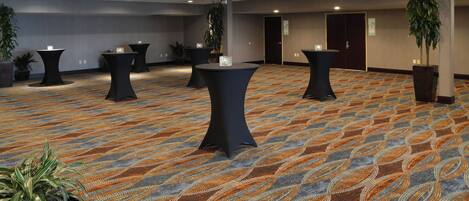 A conference room with multiple tables, chairs, and potted plants.
