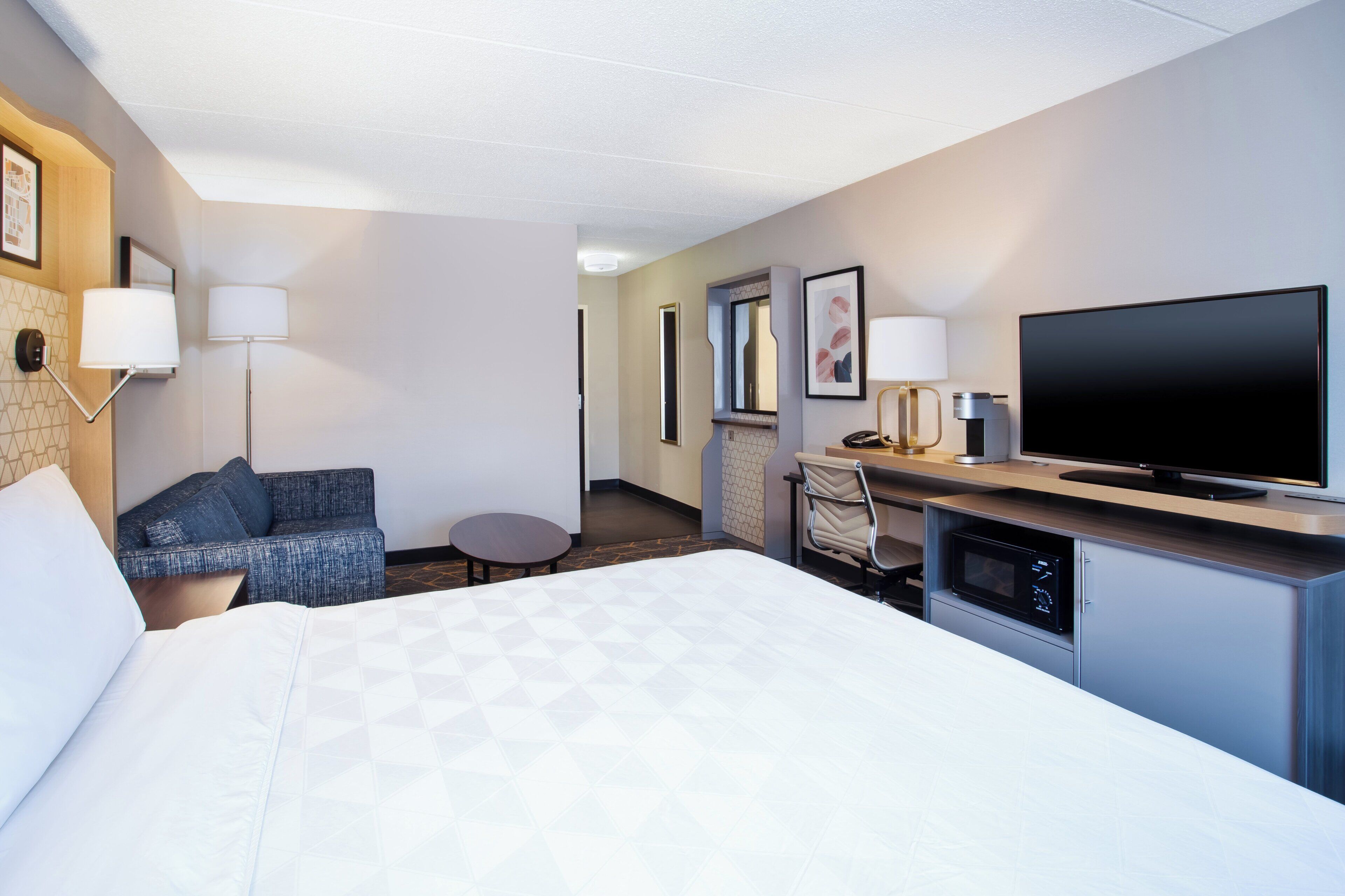 A hotel room with a bed, a desk, a television, and a chair.