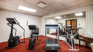 Academia com máquinas de cardio, esteira e espelho.