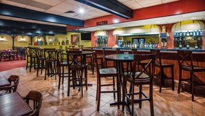 Un restaurante con zona de bar, varias mesas y sillas, y una barra visible con botellas.