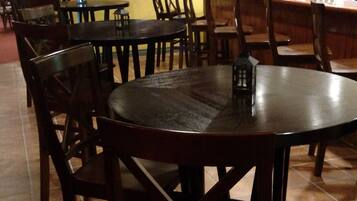 L’intérieur d’un restaurant avec des tables et des chaises rondes, un comptoir sur lequel est affiché un panneau indiquant « BISTROT », et un sol carrelé.