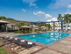 A hotel pool area with lounge chairs, umbrellas, and a clear blue sky. - Novotel Manaus (Manaus)