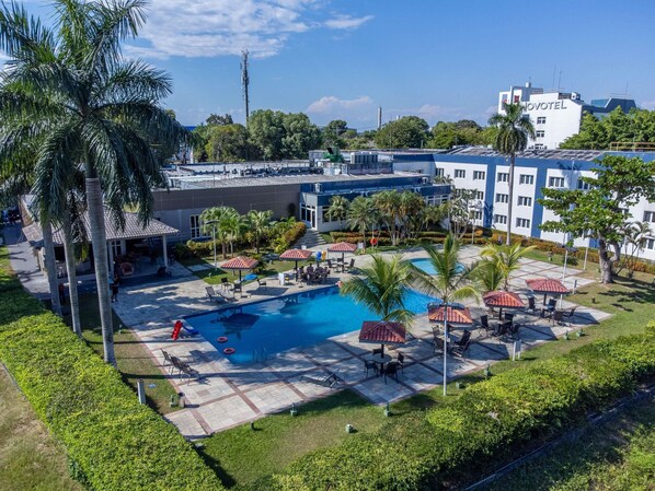 Un hotel con piscina, mobiliario exterior y palmeras.