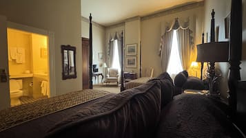 Ein Hotelzimmer mit einem großen Bett, einer Sitzecke mit einem Sessel, einem Schreibtisch und einem Fernseher.