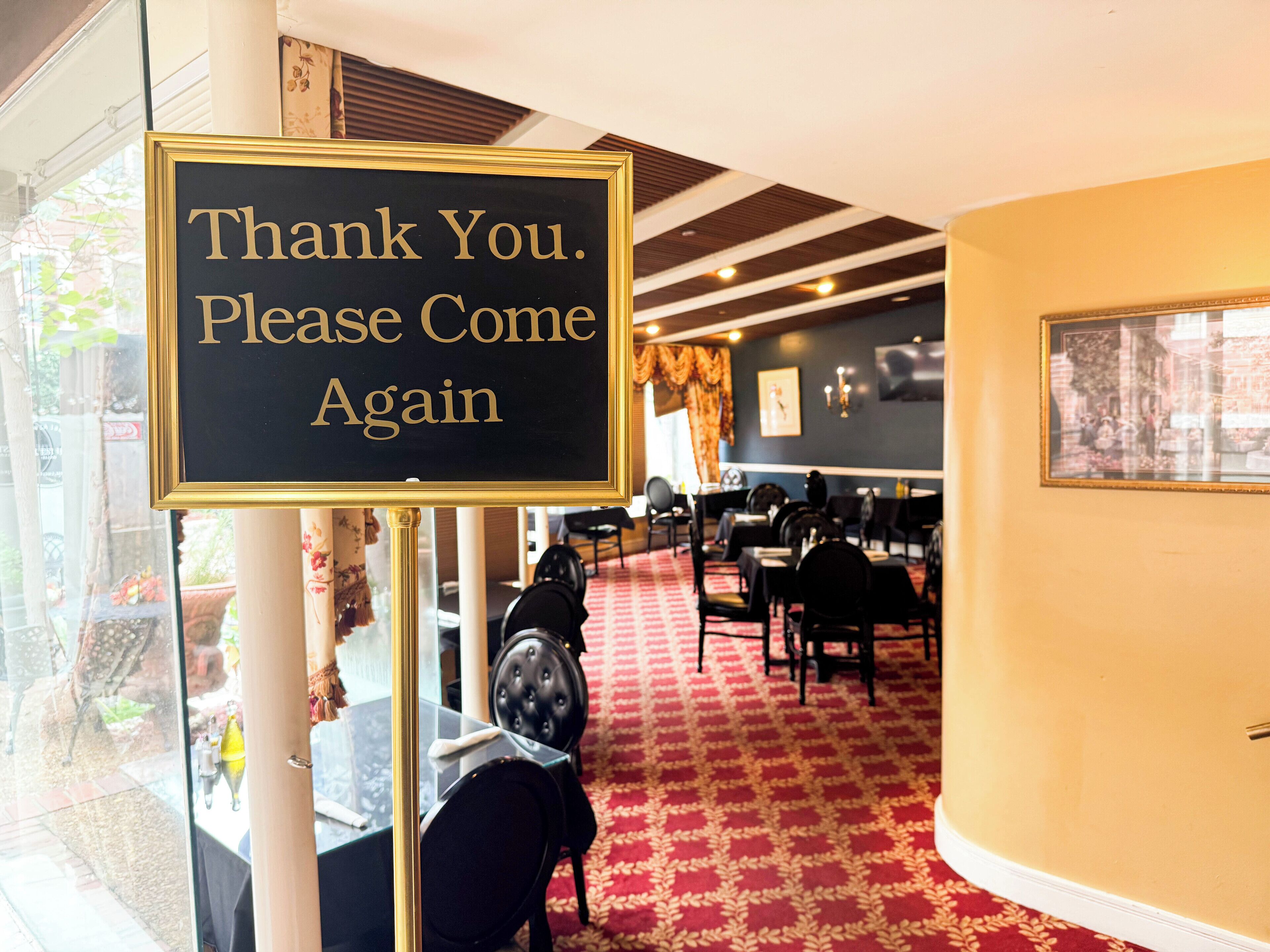A restaurant interior with a sign reading "Thank You. Please Come Again" and a red carpeted floor.