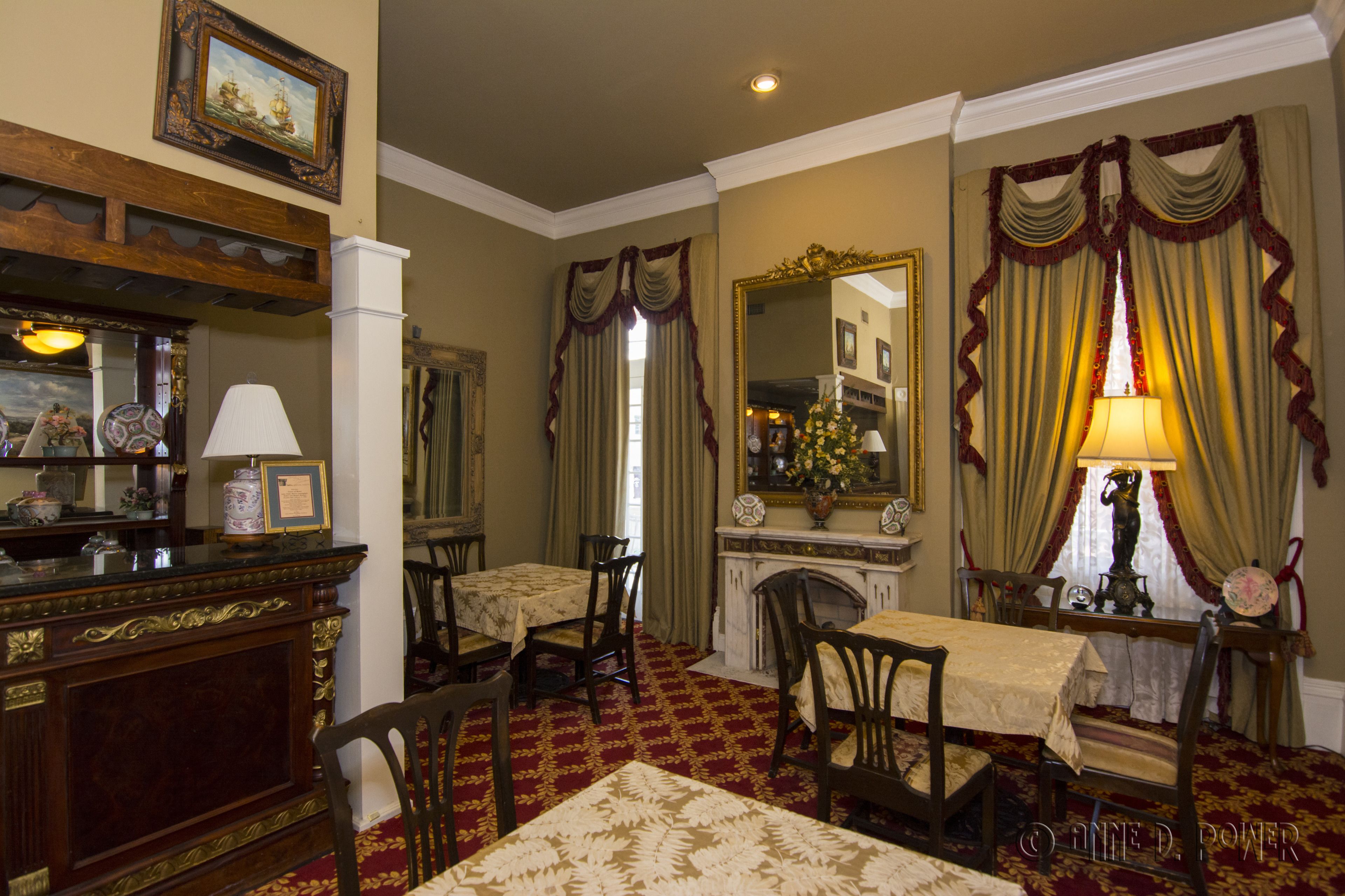 Une salle à manger élégante, dotée d’une cheminée, d’une table dressée pour quatre personnes et d’un miroir au-dessus du manteau de cheminée.