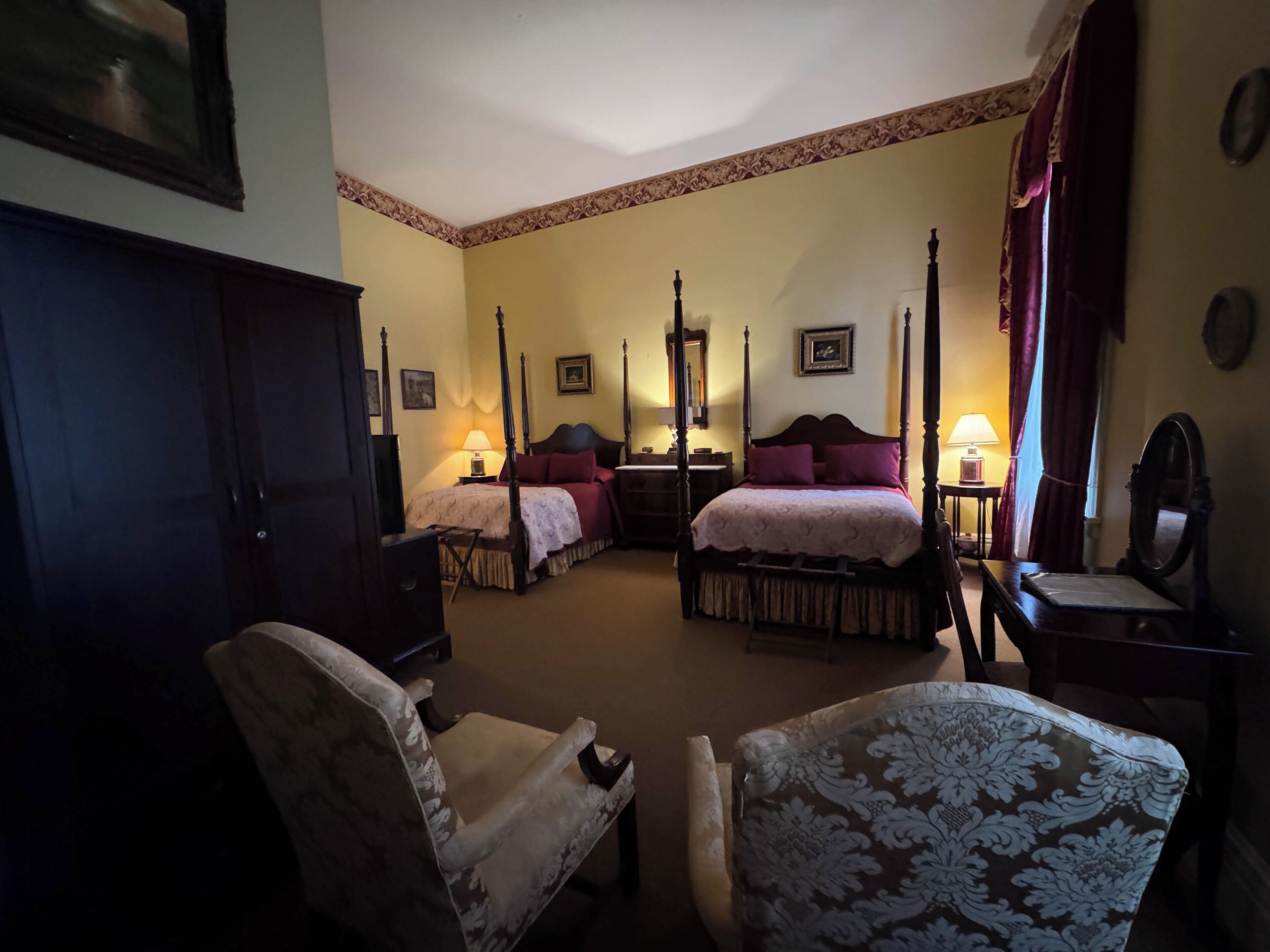 Een hemelbed met een baldakijn, twee nachtkastjes, een stoel en een spiegel.