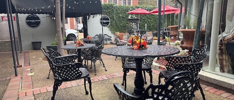 A patio area with round tables and chairs, a covered seating area, and a building with a sign reading "The Guest House".