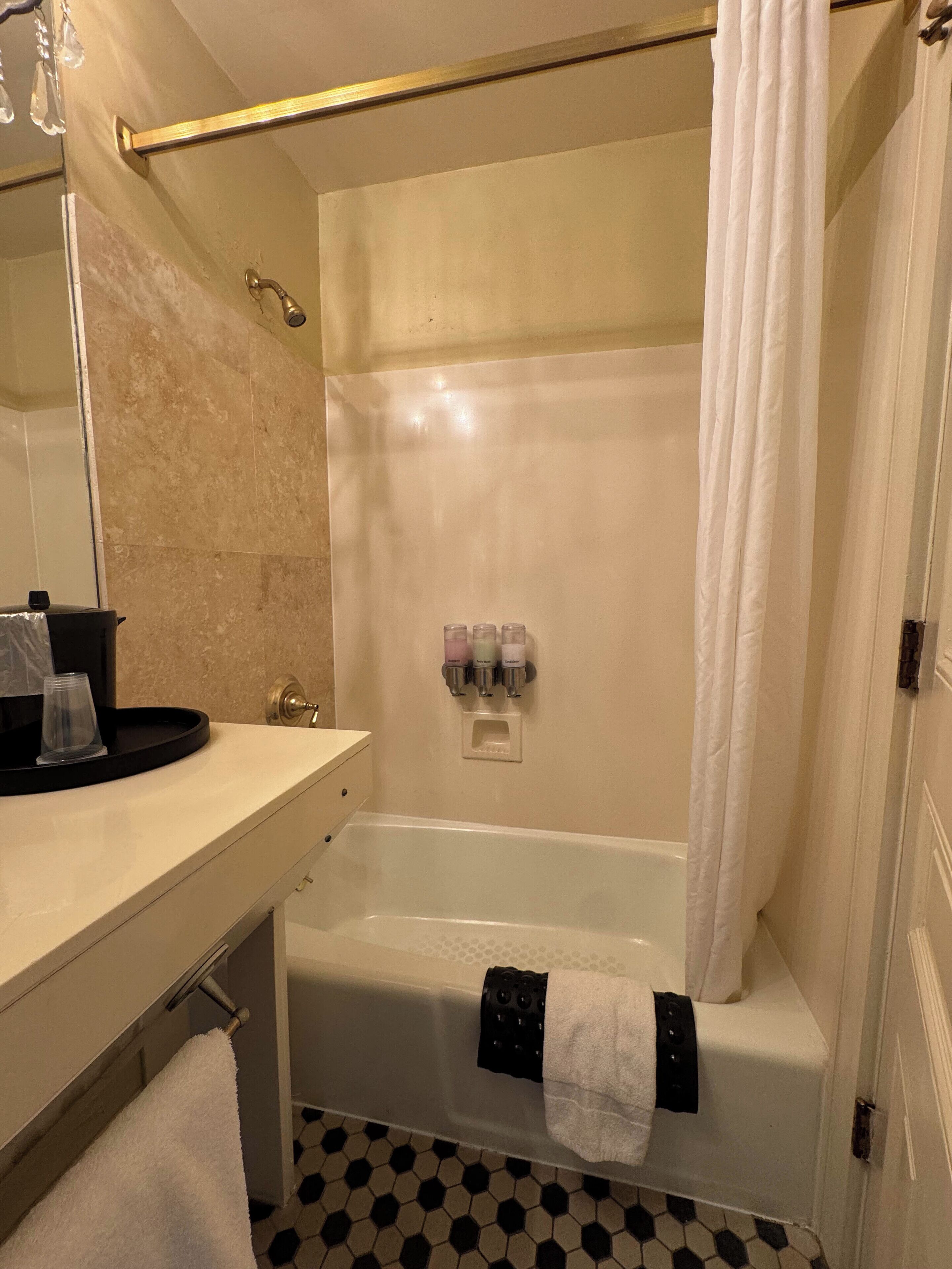 Une salle de bain avec une baignoire, un rideau de douche, un porte-serviettes et un lavabo avec un miroir.