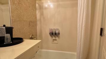 Une salle de bain avec une baignoire, un rideau de douche, un porte-serviettes et un lavabo avec un miroir.