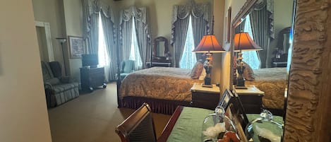 Habitación de hotel con una cama grande, una silla, un escritorio con lámpara, un espejo y un frutero.