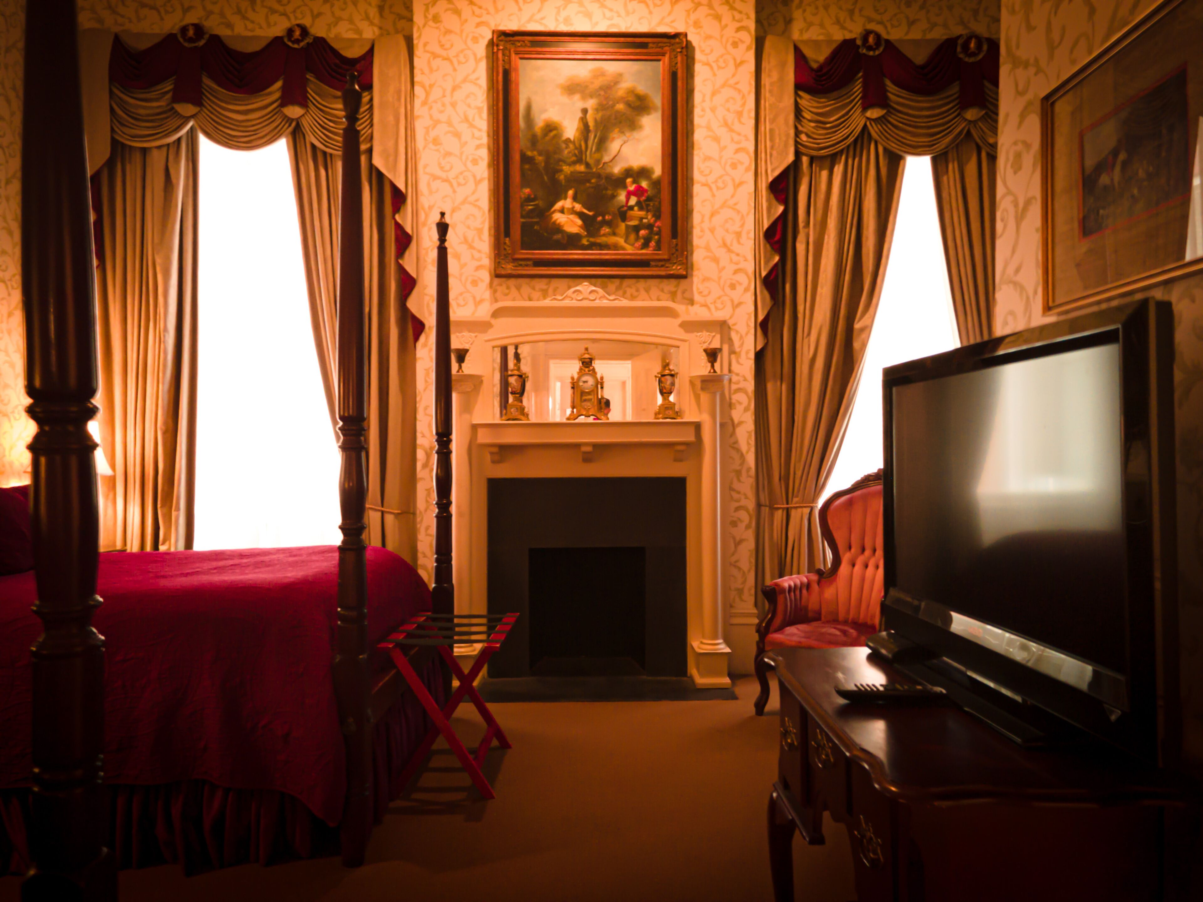 Una habitación de hotel con cama, televisión, chimenea y cortinas.