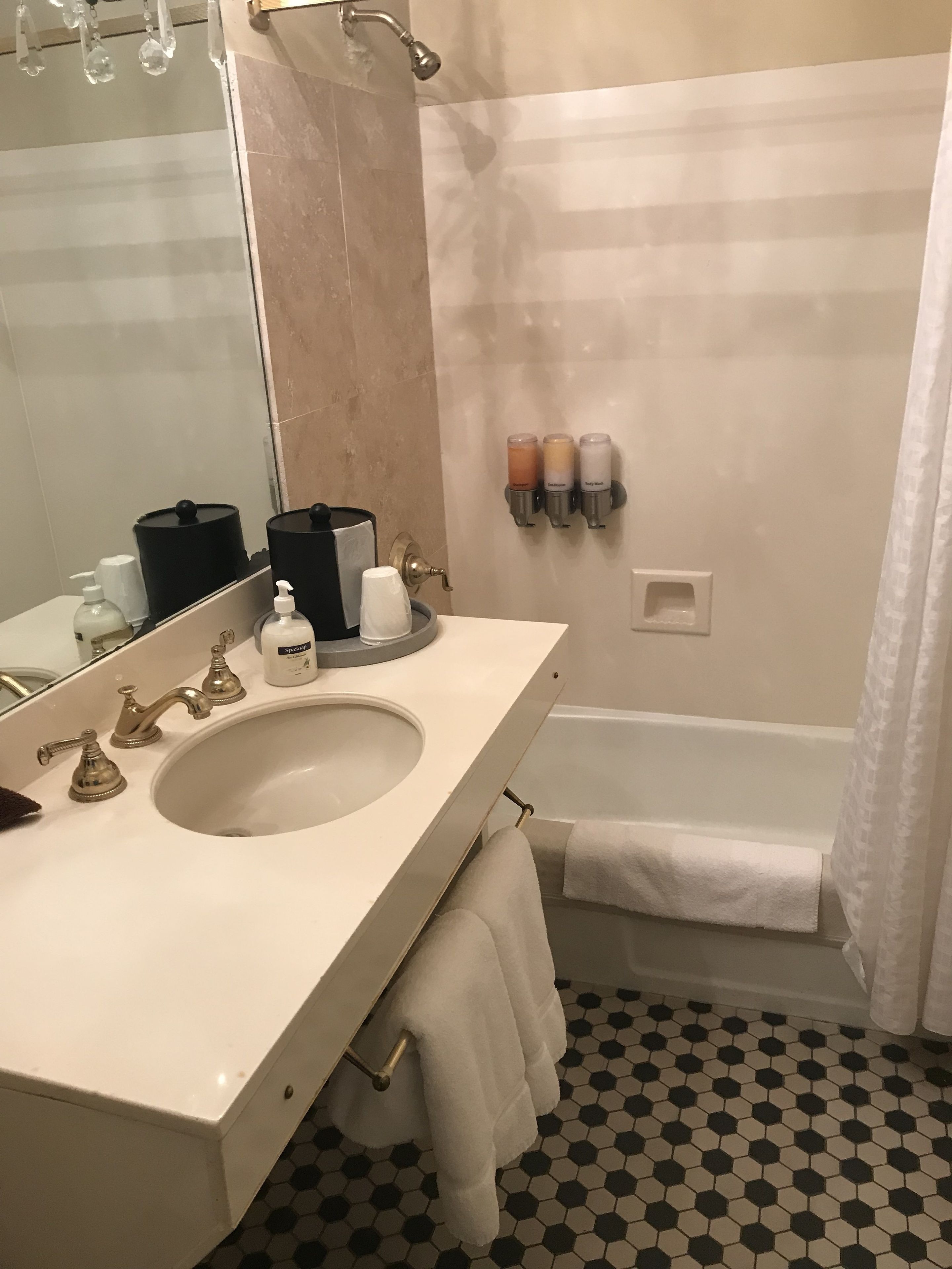 A bathroom with a large sink, a mirror, a shower, and a towel rack.