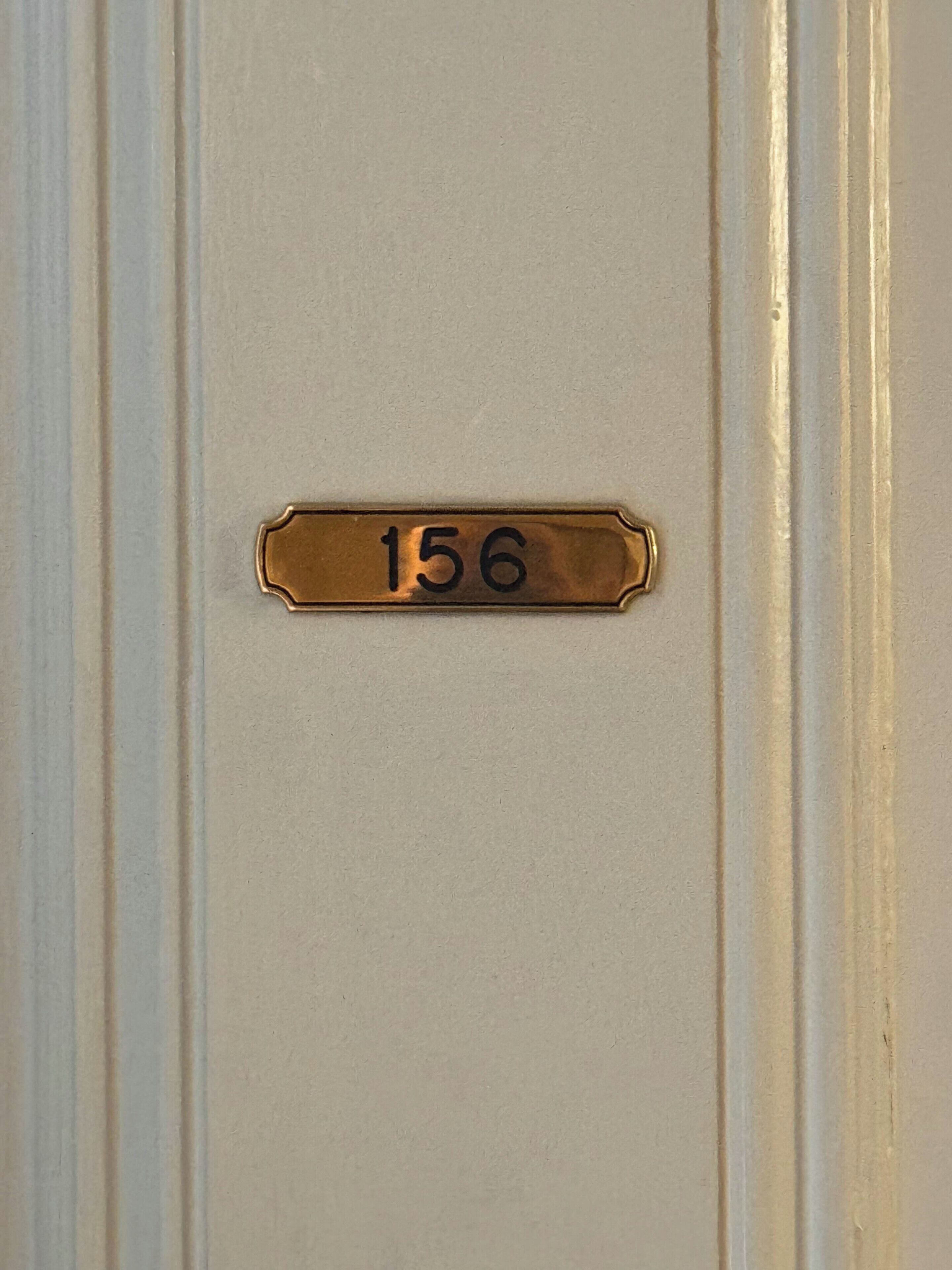 Eine Messings Türschild mit der Nummer 156.