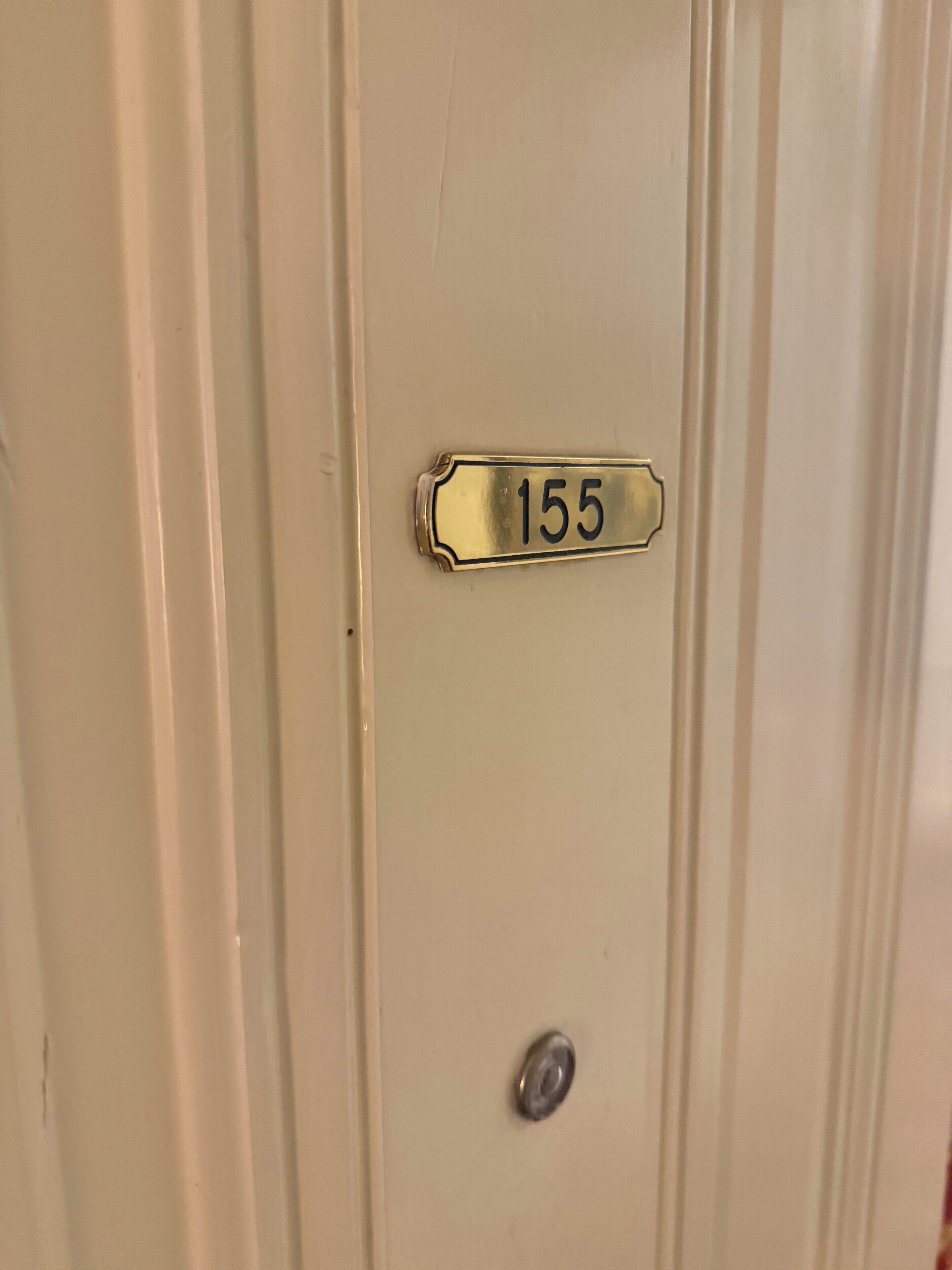 A door with a brass plate labeled "155" and a round metal handle.