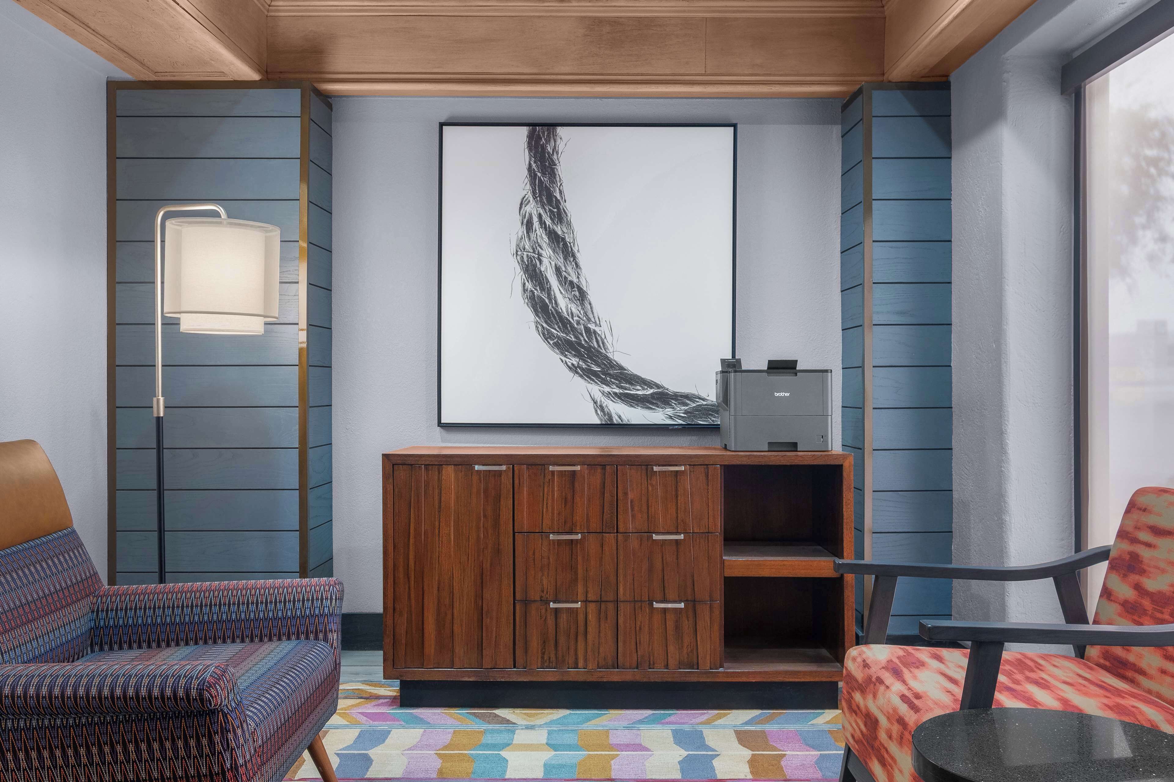 A modern living room with a patterned sofa, a wooden cabinet, and a large abstract painting on the wall.