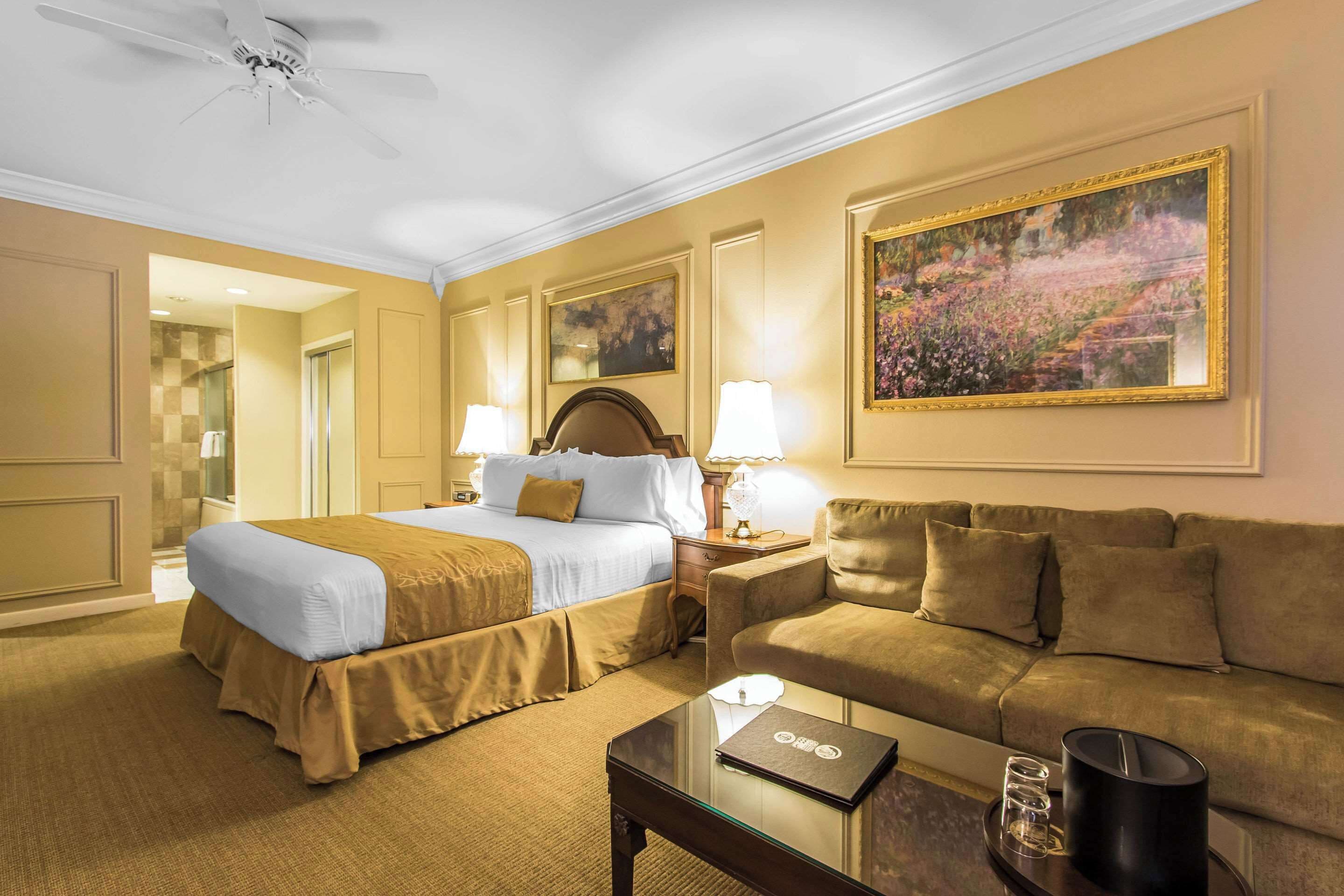 Une chambre d’hôtel avec un lit, un canapé, une table basse et un tableau au mur.