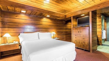 A wooden-paneled room with a bed, nightstands, a TV, and a wardrobe.